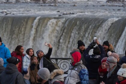 Tourists take photographs at the Horseshoe Falls in Niagara Falls, Ontario, Canada on December 28, 2022